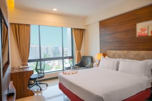 a hotel room with a bed and a desk and a window at Hotel Tip Top International Pune in Pune