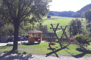 un parque infantil con un árbol y un cenador en Geigerbauernhof, en Mühlenbach