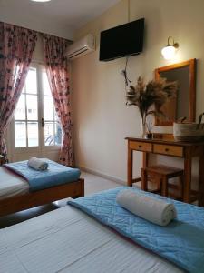 a bedroom with two beds and a desk and a television at Aquarius in Moraitika