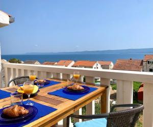 una mesa de madera con comida y bebida en el balcón en Apartments & Rooms Pierino, en Bol