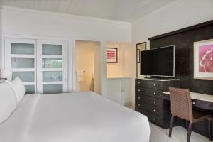 a bedroom with a bed and a desk with a television at Crystal Cove, Barbados, A Tribute Portfolio All-Inclusive Resort in Saint James