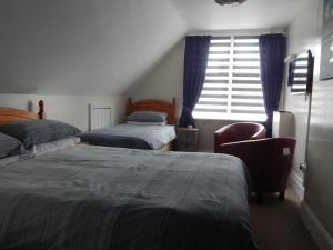 a bedroom with two beds and a chair and a window at The Garfield Guest House in Eastbourne