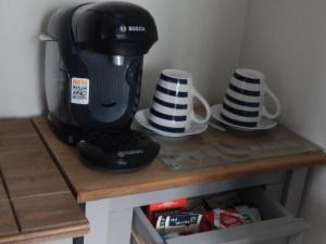 een koffiezetapparaat en twee kopjes op een tafel bij The Garfield Guest House in Eastbourne