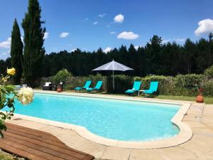 a swimming pool with blue chairs and an umbrella at Chez Louis Gites in Fumel