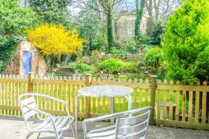 a table and chairs in a garden with a fence at The Cottage by The Walls in York