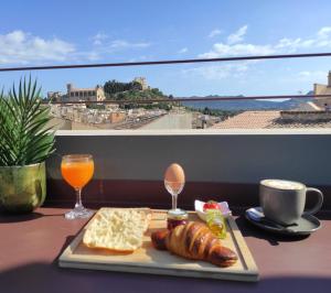 a plate of food with bread and orange juice and a view at Ōrigins Hotel Boutique - Adults Only in Artá
