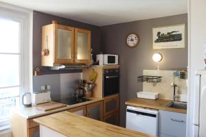 a kitchen with wooden cabinets and a counter top at L'entre port & mer - Vue mer - Proxi gare plage & quai - Hyper-Centre - Parking gratuit in Dieppe