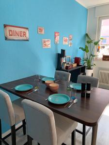 a dining room table with chairs and a blue wall at Zentral 72qm Style Küche Boxspringbett 1 Parkplatz in Osnabrück