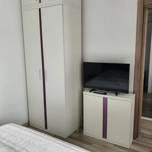 una camera da letto con TV e armadio bianco di Summerland Apartament a Mamaia
