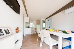 una cucina e una sala da pranzo con tavolo e sedie bianchi di New Campsite in Camping Ca' Savio a Cavallino-Treporti