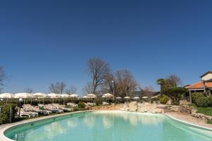 ein großer Pool mit Stühlen und Sonnenschirmen in einem Resort in der Unterkunft Abbazia Collemedio Resort & Spa in Collazzone