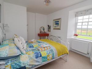 ein Schlafzimmer mit einem Bett mit einer Steppdecke darauf in der Unterkunft Seaview-Barsloisnach Cottage in Kilmartin