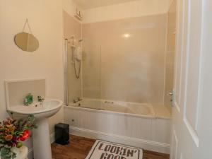 a bathroom with a shower and a tub and a sink at Seaview-Barsloisnach Cottage in Kilmartin