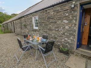 einen Tisch und Stühle vor einem Steingebäude in der Unterkunft Seaview-Barsloisnach Cottage in Kilmartin