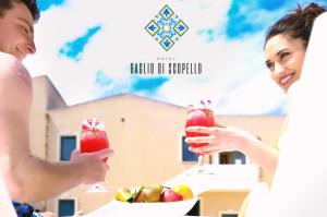 una sposa e uno sposo che bevono cocktail a un tavolo con un cesto di frutta di Hotel Baglio Di Scopello a Scopello