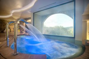 a hot tub with a waterfall in a room with a window at Abbazia Collemedio Resort & Spa in Collazzone