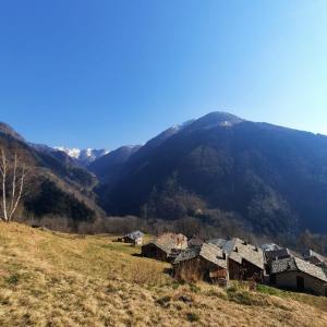 un grupo de casas en una colina con una montaña en Baita Autentica - Your Mountain Holiday, en Premana