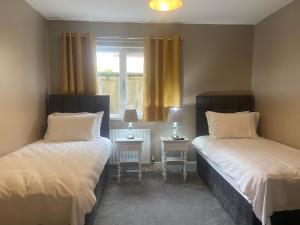 two beds in a room with two tables and a window at Bayview Apartments in Ballygalley