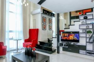 a living room with a tv and a red chair at Huge Loft Type Condo At Queen City of the South in Cebu City