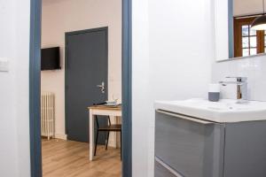 a bathroom with a sink and a desk with a mirror at Le Descartes, à 50m de la gare Fibre/TV connecté in Poitiers