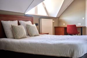 1 dormitorio con cama blanca y silla roja en B&B Abdeshof, en Middelkerke