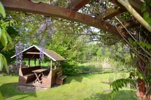 un cenador de madera en un jardín con flores púrpuras en Ferienhof Sommergarten, en Markische Heide
