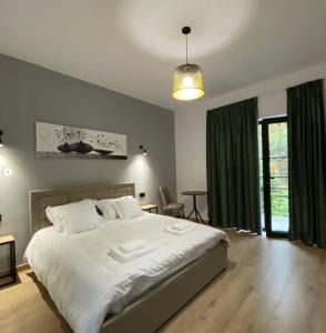 a bedroom with a large white bed and green curtains at Vila Jasmine in Tirana