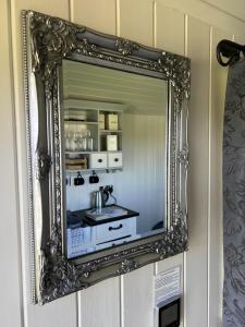 um espelho numa parede com um lavatório em Home Farm Shepherds Hut with Firepit and Wood Burning Stove em High Wycombe