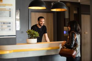 Un homme debout au comptoir avec une femme dans l'établissement Oneloft Hotel, à Obernai