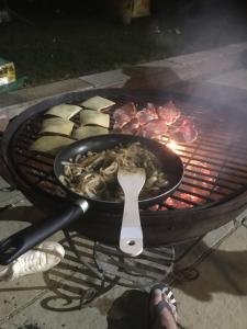 a pan of food on a grill with meat and vegetables at Home Farm Shepherds Hut with Firepit and Wood Burning Stove in High Wycombe