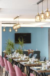 uma sala de jantar com mesas de madeira e cadeiras cor-de-rosa em MAIA HOTEL SUITES em Tunes