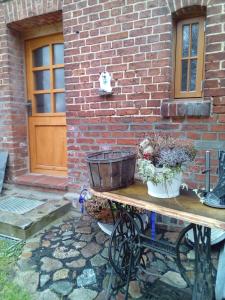 a table with a bucket and flowers on it next to a brick building at Ferienwohnung Fuchsberge in Letschin