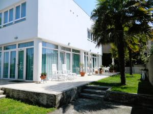 a white house with white chairs and a palm tree at Villa Marina in Venice-Lido