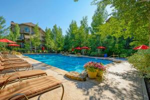 a swimming pool with chairs and red umbrellas at 306 Aspenwood Lodge in Edwards