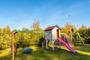 a playground with a slide and a play house at Domki Biała Perła in Rusinowo