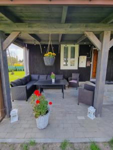 a patio with a couch and a table and flowers at Domek Mazury Pisz in Pisz