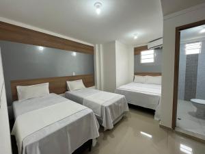 a hotel room with two beds and a bathroom at HOTEL PINHEIRO CENTER in Pinheiro