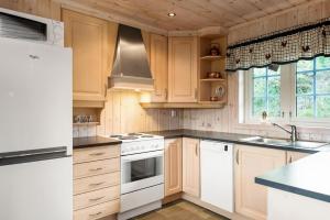a kitchen with white appliances and wooden cabinets at ReveEnka - cabin in Trysil with Jacuzzi for rent in Trysil