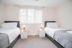 two beds in a room with white walls and a window at Potter Apartment in Doncaster