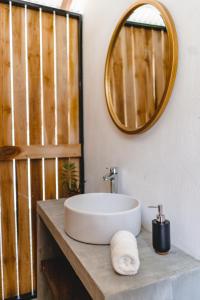 a bathroom with a sink and a mirror on a counter at Cuatro Vientos Lodge & Apartments in Santa Teresa Beach