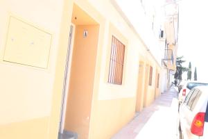 a narrow street with cars parked on the side of a building at ALAUDAE Apartamentos in Merida