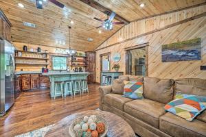 a living room with a couch and a kitchen at Setting Sun Cabin with Private River Access in Eagletown