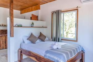 een slaapkamer met een bed met witte lakens en een raam bij Cuatro Vientos Lodge & Apartments in Santa Teresa Beach