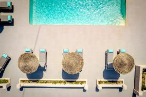 a group of chairs with hayrolls on a wall at En Plo Boutique Suites in Oia