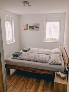 Bett in einem Zimmer mit 2 Fenstern in der Unterkunft Creek House in Müllheim