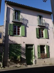 un edificio blanco con persianas y ventanas verdes en Le Midi 2, en Trèbes