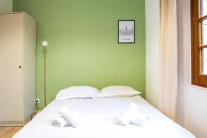 a white bed in a room with a green wall at Le Mélusine , à 50m de la gare de Poitiers in Poitiers