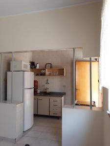 a kitchen with a white refrigerator and a counter at Casa do Peregrino - Confortável no centro in Paraisópolis