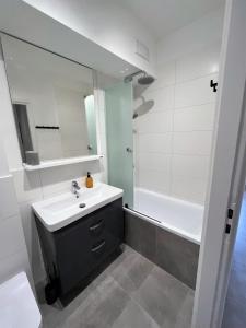 a bathroom with a sink and a mirror and a tub at Apartament RZ in Gdynia