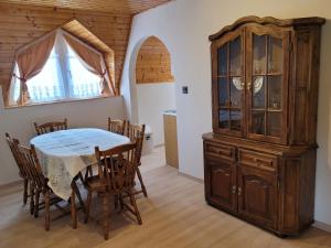 a dining room with a table and a china cabinet at Henrietta Apartmanház in Zalakaros +12 photos